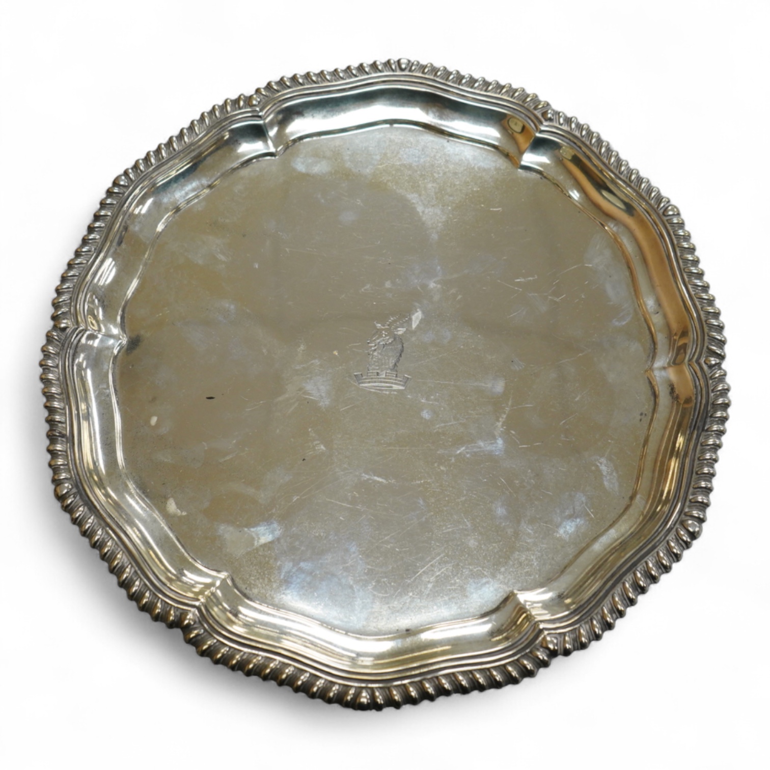 A George V silver salver, by Elkington & Co, of shaped circular form, with engraved crest, on three scroll feet, diameter 26.2cm, 18.7oz.